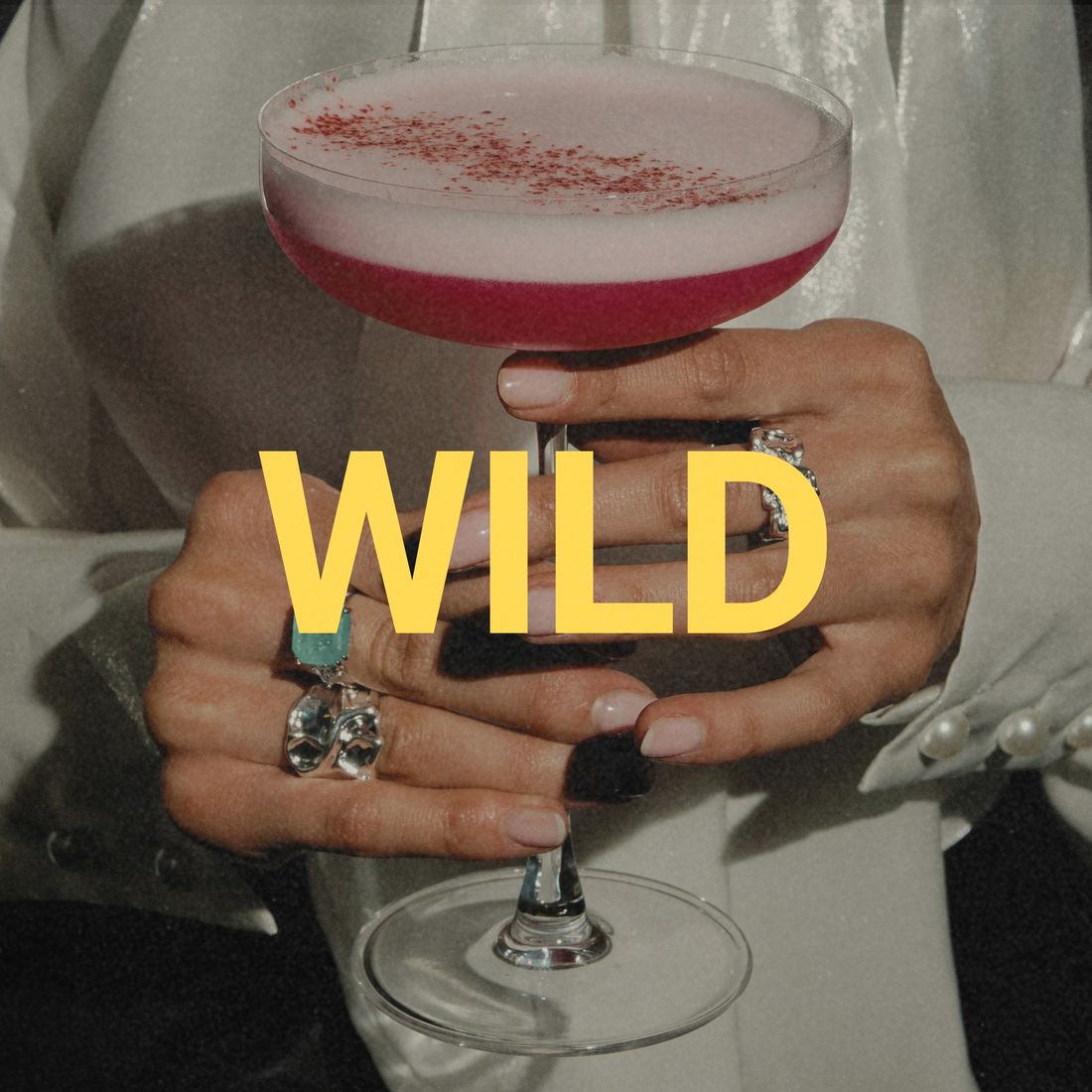 Wild mode: hands with silver rings holding a pink cocktail